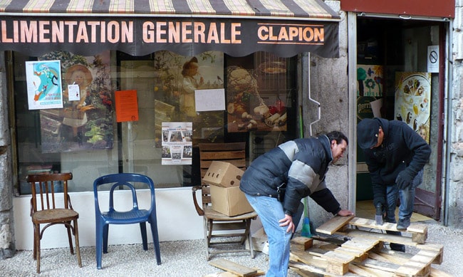 Devanture de l'épicerie Alimentation générale Clapion rue Saint Laurent à Grenoble avec deux hommes cassant des palettes de bois sur le trottoir © Delphine Chappaz - placegrenet.fr