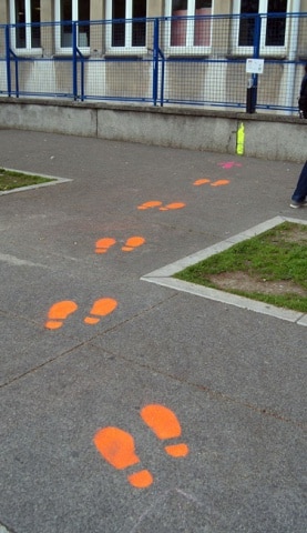 Traces de pas réalisées au pochoir et à la peinture fluo pour inciter les élèves à jeter leurs mégots dans les cendriers en vue de leur recyclage par Terracycle