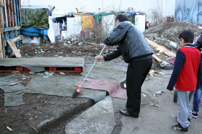 Un homme balaye devant l'église faite en palettes de bois dans le camp abritant des Roms et des sans abris à Grenoble.