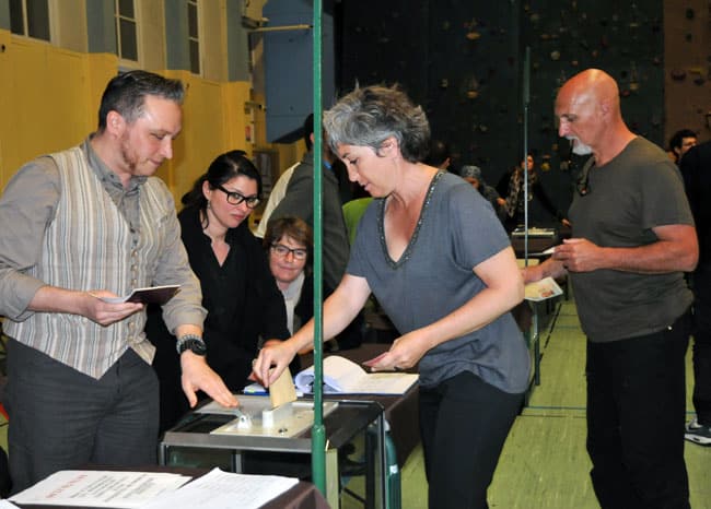 Une électrice s'apprête à déposer son bulletin dans l'urne face à un assesseur dans un Bureau de vote à Grenoble à l'occasion du second tour des élections départementales © Muriel Beaudoing - placegrenet.fr