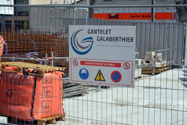 Panneau sur une grille d'un chantier bâtiment et travaux publics sur le chantier de la gare à Grenoble. © Sidonie Hadoux