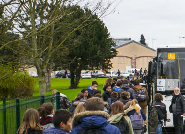 Un groupe d'élèves s'apprête à monter dans un bus scolaire. DR