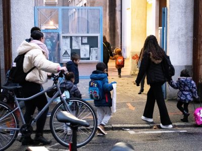 Des mamans à pied et à vélo amenant leurs enfants à l'école pour la rentrée des vacances de Noel.