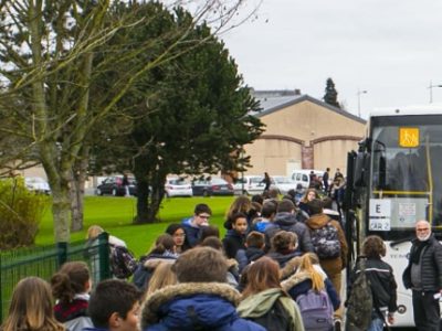 Un groupe d'élèves s'apprête à monter dans un bus scolaire. DR